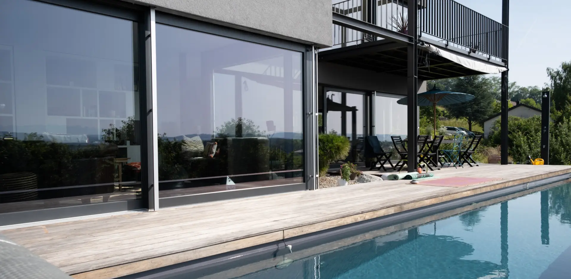 Menuiserie sur la terrasse et baies vitrées d'une maison moderne avec piscine.