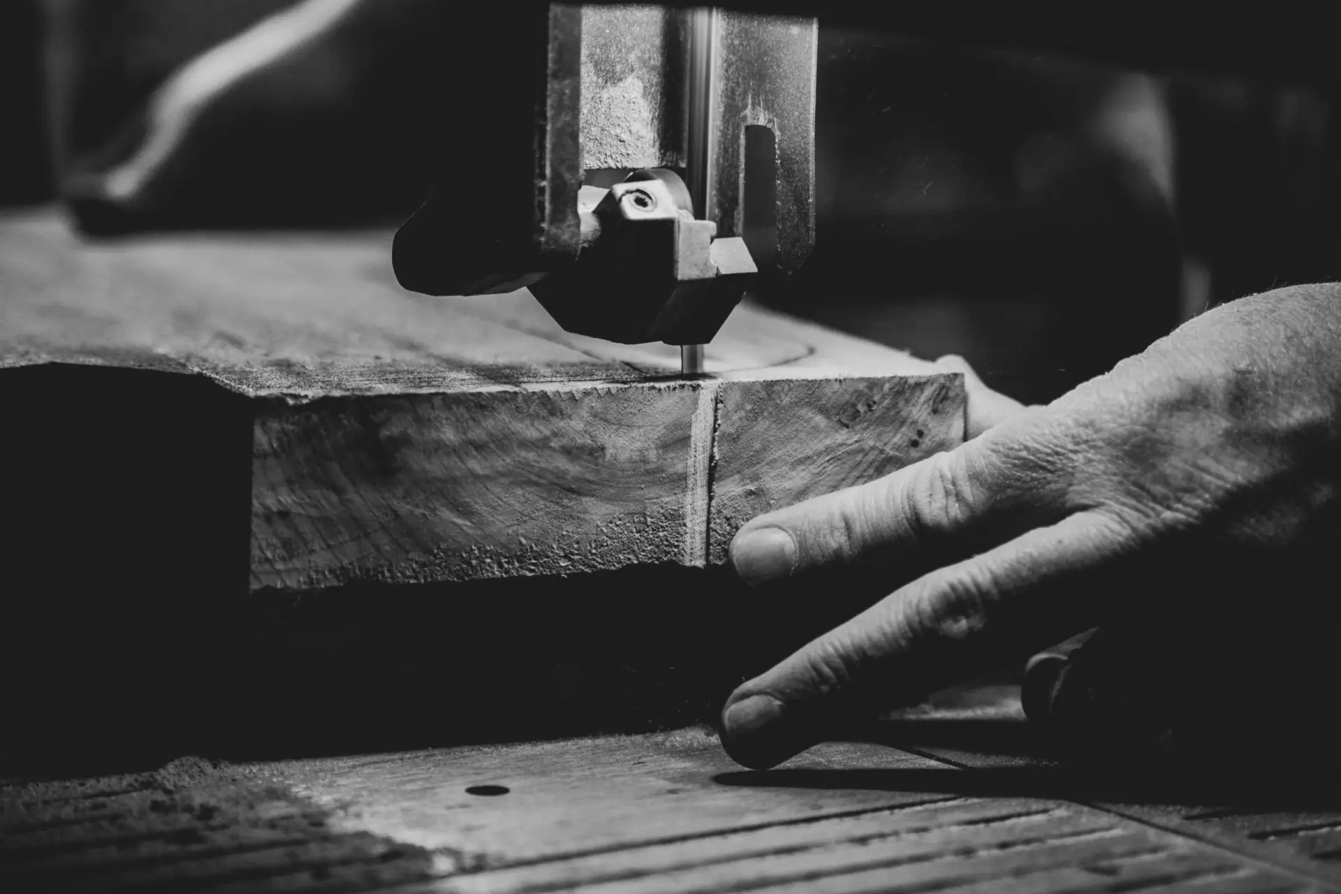 Mains de menuisier découpant du bois à l'aide d'une machine.